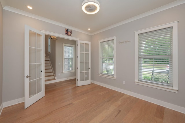 spare room featuring crown molding, light wood-style flooring, french doors, baseboards, and stairway