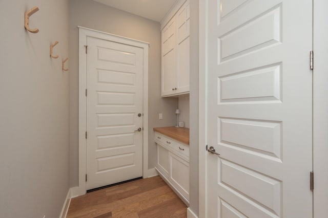 doorway to outside featuring baseboards and light wood finished floors