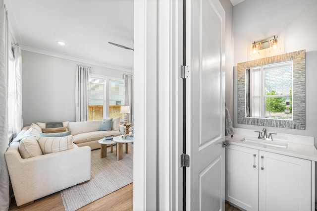 bathroom featuring plenty of natural light, wood finished floors, ornamental molding, vanity, and recessed lighting