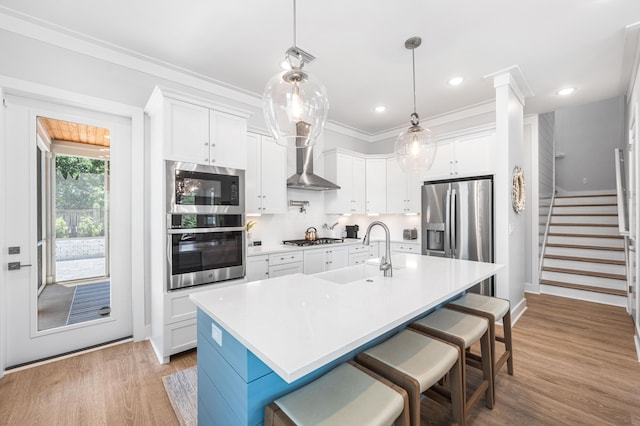 kitchen with appliances with stainless steel finishes, a sink, light wood-style flooring, light countertops, and crown molding