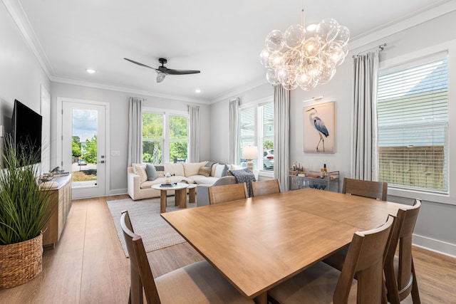 dining space with light wood-style flooring, ceiling fan, ornamental molding, a chandelier, and baseboards