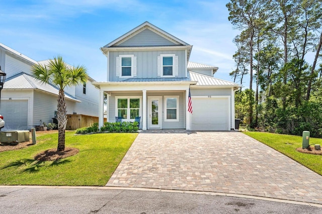 traditional-style house with board and batten siding, decorative driveway, a garage, and a front lawn