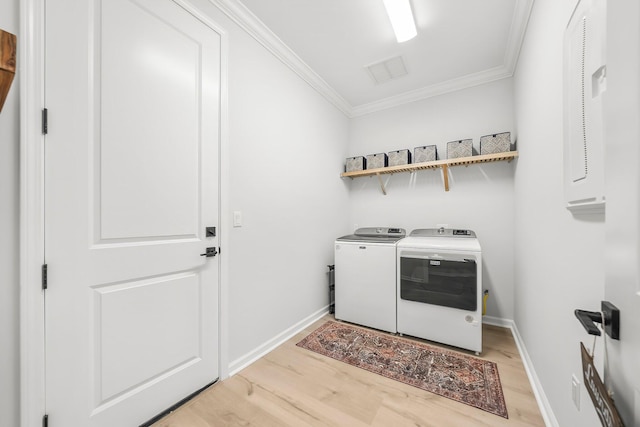 laundry area featuring laundry area, crown molding, washing machine and dryer, baseboards, and light wood-type flooring