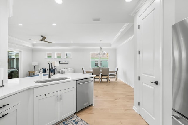 kitchen featuring crown molding, a sink, light wood-style floors, and appliances with stainless steel finishes