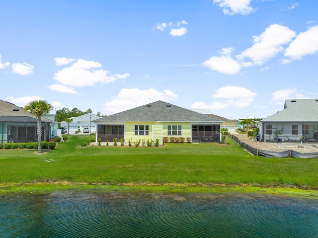 rear view of house featuring a sunroom, a water view, and a yard