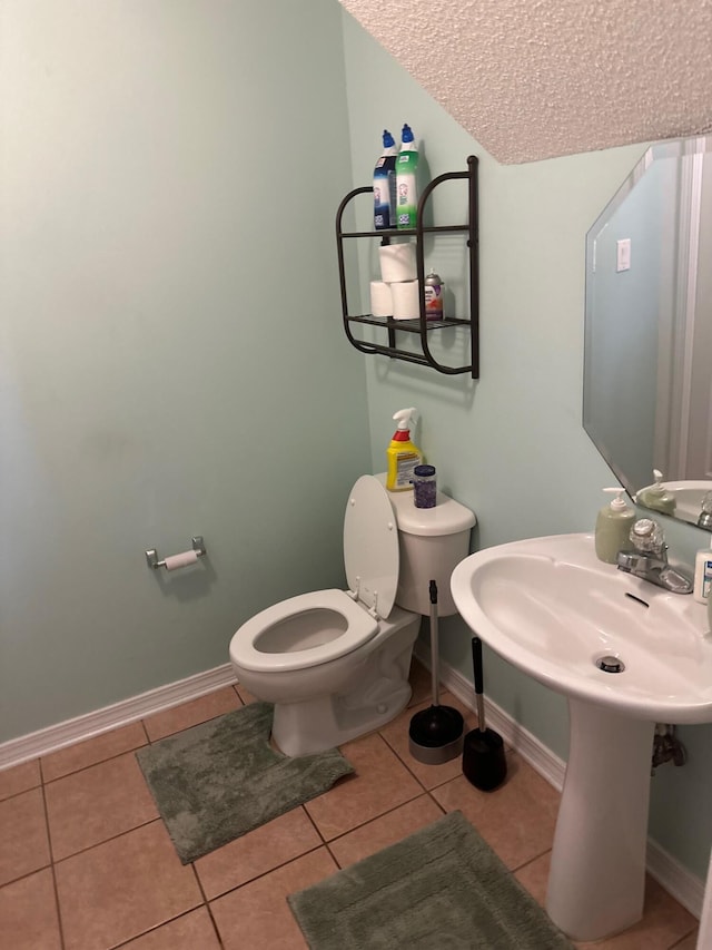 bathroom with toilet, a textured ceiling, tile patterned floors, and baseboards