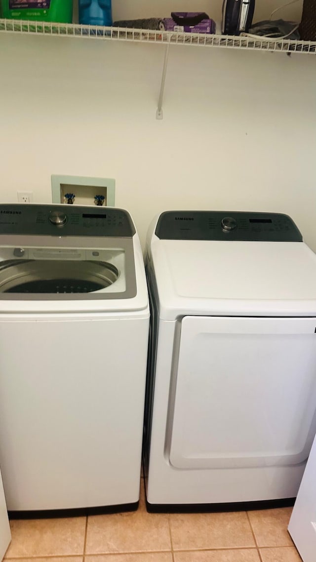 laundry room featuring light tile patterned floors, laundry area, and independent washer and dryer