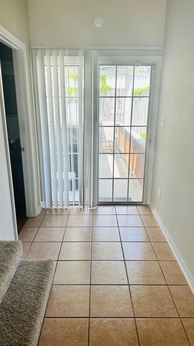 doorway to outside with tile patterned flooring and baseboards