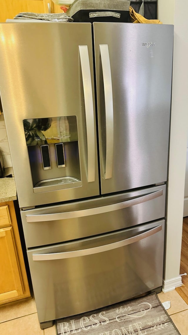 interior details featuring light stone countertops and stainless steel fridge with ice dispenser