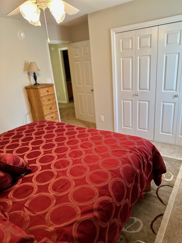 bedroom with light colored carpet, a ceiling fan, and a closet
