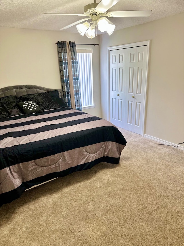 carpeted bedroom featuring a closet, a ceiling fan, and a textured ceiling