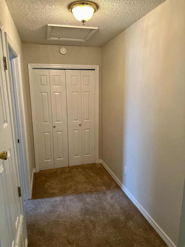 entryway featuring a textured ceiling, carpet, and baseboards