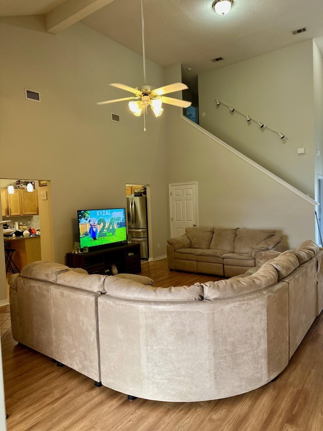 living area with high vaulted ceiling, ceiling fan, and visible vents