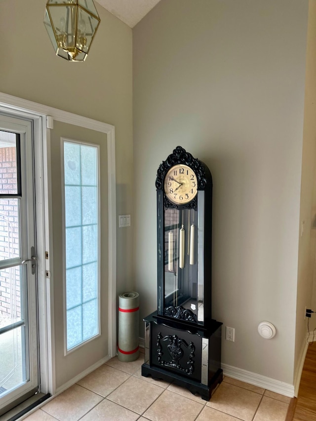 entryway featuring baseboards, a notable chandelier, a wealth of natural light, and light tile patterned flooring