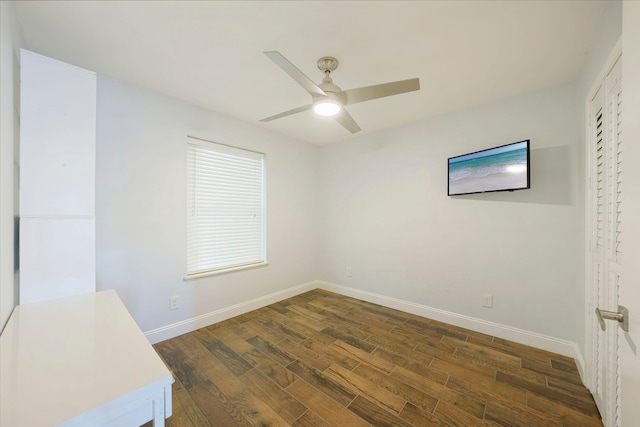 unfurnished room with baseboards, ceiling fan, and dark wood-type flooring