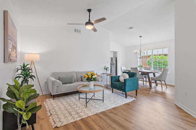living room with visible vents, wood finished floors, baseboards, high vaulted ceiling, and ceiling fan with notable chandelier