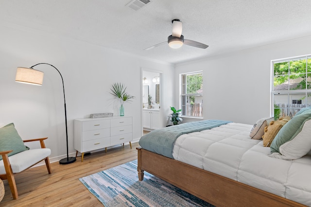bedroom featuring light wood-style floors, multiple windows, ornamental molding, and visible vents