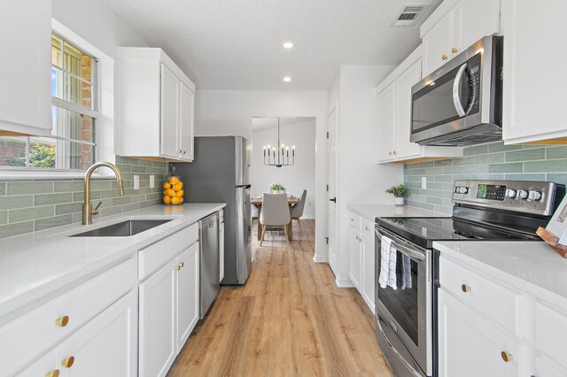 kitchen featuring visible vents, white cabinetry, a sink, light wood finished floors, and stainless steel appliances