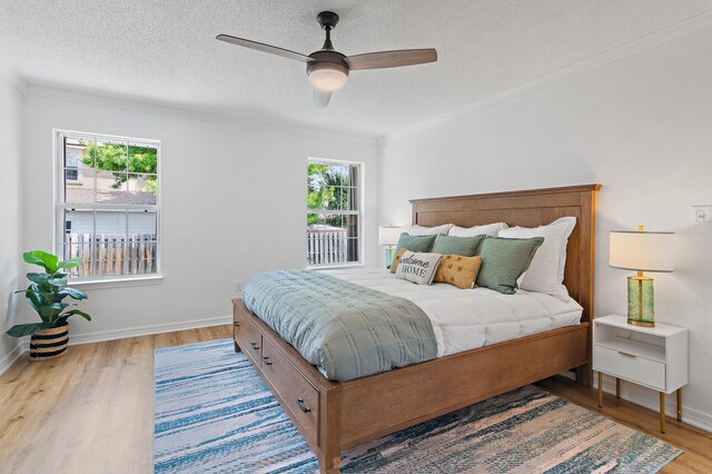 bedroom with crown molding, wood finished floors, baseboards, ceiling fan, and a textured ceiling