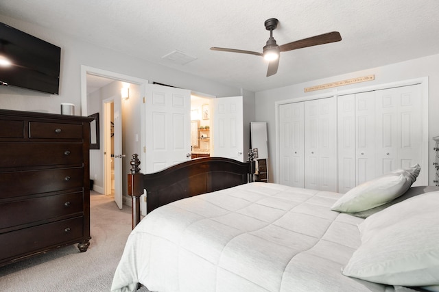 bedroom featuring a closet, visible vents, ceiling fan, connected bathroom, and light colored carpet