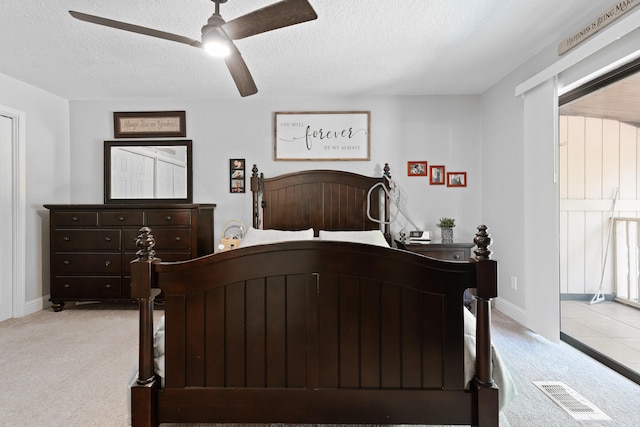 bedroom with ceiling fan, a textured ceiling, carpet, and visible vents