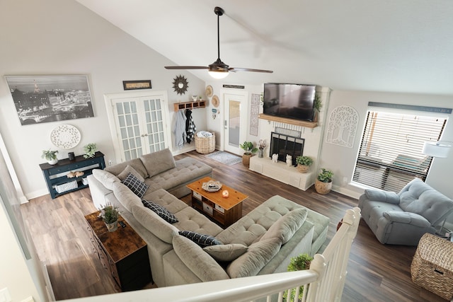 living room featuring a ceiling fan, french doors, baseboards, wood finished floors, and a large fireplace