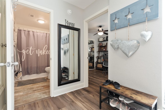hallway featuring visible vents, wood finished floors, and baseboards