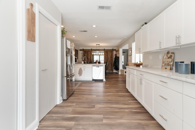 kitchen featuring a peninsula, a sink, stainless steel refrigerator with ice dispenser, visible vents, and dishwasher