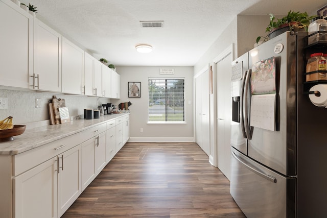 kitchen featuring white cabinetry, stainless steel fridge, visible vents, and dark wood finished floors