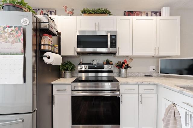 kitchen with light stone counters, white cabinets, and appliances with stainless steel finishes