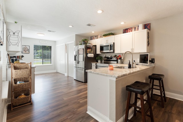 kitchen featuring a sink, visible vents, dark wood-style floors, baseboards, and appliances with stainless steel finishes