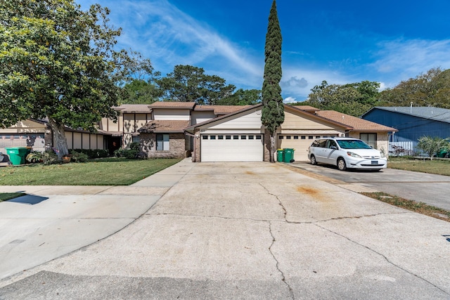 view of front of house featuring a front lawn, driveway, brick siding, and a garage