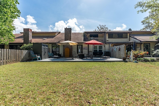 rear view of property featuring a yard, fence, a chimney, and a patio area