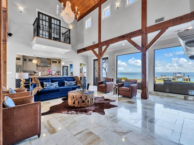 living area featuring visible vents, a healthy amount of sunlight, a notable chandelier, and a high ceiling
