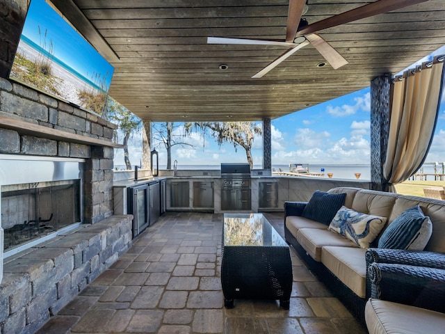 view of patio with exterior kitchen, area for grilling, an outdoor living space with a fireplace, and a sink