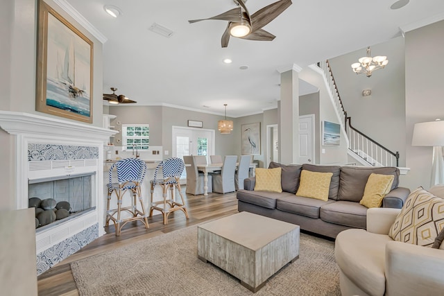597 Avalon Blvd, Miramar Beach, FL 32550 - living room featuring visible vents, stairway, ceiling fan with notable chandelier, light wood finished floors, and ornamental molding