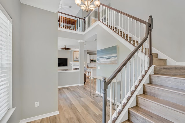 597 Avalon Blvd, Miramar Beach, FL 32550 - staircase with baseboards, wood finished floors, ceiling fan with notable chandelier, and a towering ceiling