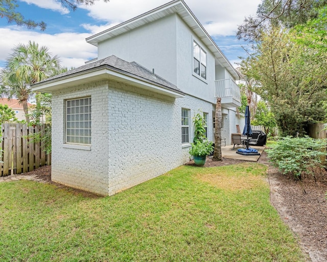 597 Avalon Blvd, Miramar Beach, FL 32550 - view of property exterior featuring brick siding, a lawn, fence, and a patio