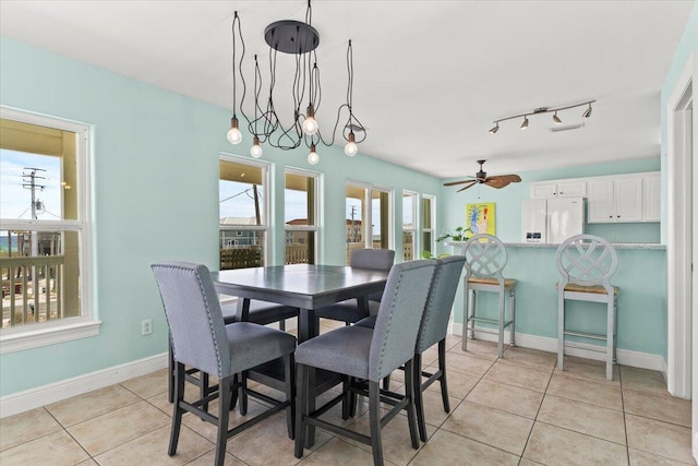 8054 Gulf Blvd, Navarre, FL 32566 - dining space with baseboards, rail lighting, ceiling fan, and light tile patterned floors