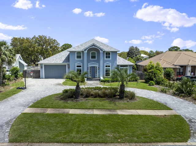 view of front facade featuring stucco siding, fence, curved driveway, and a front lawn