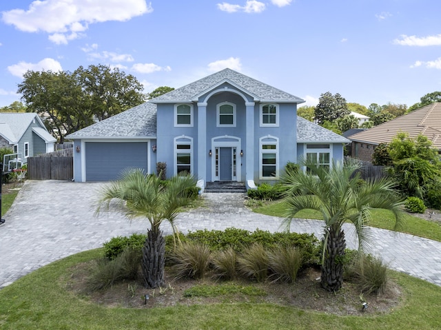 view of front of property with fence, stucco siding, a shingled roof, an attached garage, and driveway