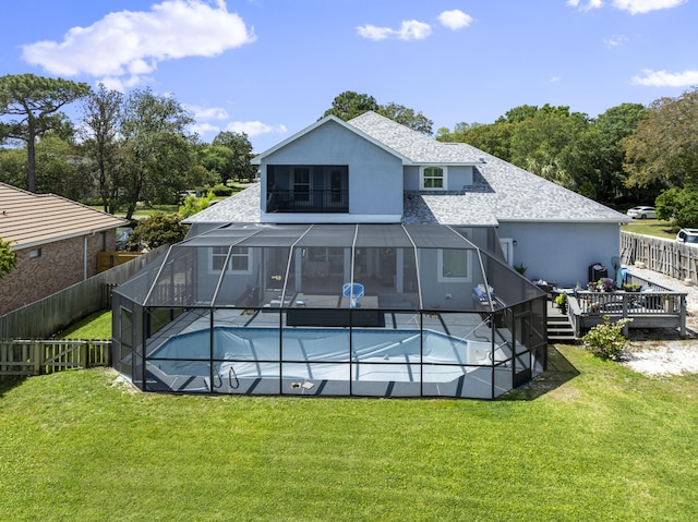 rear view of house with a fenced in pool, a shingled roof, and a lawn