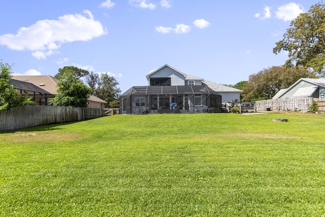 back of house featuring a lawn, a lanai, and a fenced backyard