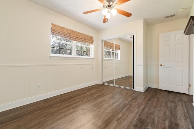 361 NE Gardner Dr, Fort Walton Beach, FL 32548 - unfurnished bedroom featuring dark wood-style floors, a closet, baseboards, a ceiling fan, and wainscoting