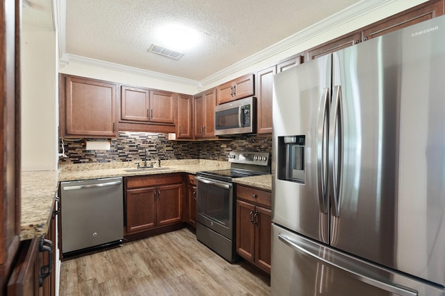 361 NE Gardner Dr, Fort Walton Beach, FL 32548 - kitchen featuring stainless steel appliances, a sink, a textured ceiling, light wood-style flooring, and crown molding