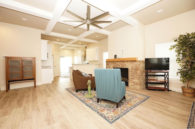 living area featuring a brick fireplace, beamed ceiling, light wood-style flooring, and coffered ceiling