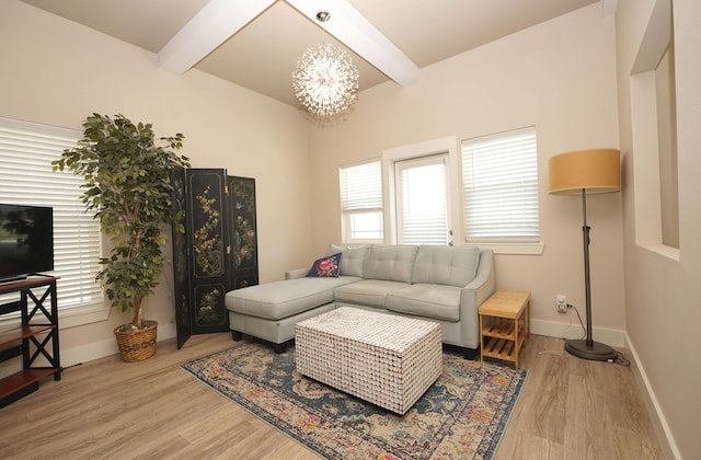 living area featuring baseboards, a notable chandelier, beam ceiling, and light wood finished floors