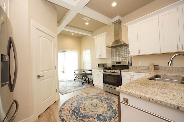kitchen with wall chimney range hood, appliances with stainless steel finishes, a sink, beamed ceiling, and coffered ceiling
