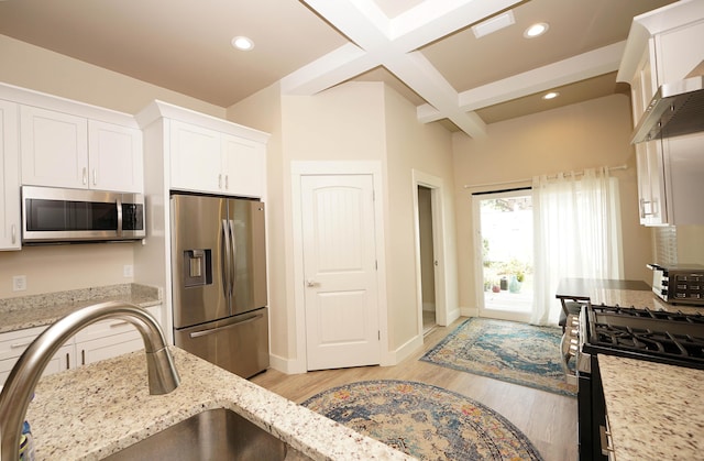 kitchen with light wood-style floors, white cabinets, light stone counters, a sink, and stainless steel appliances