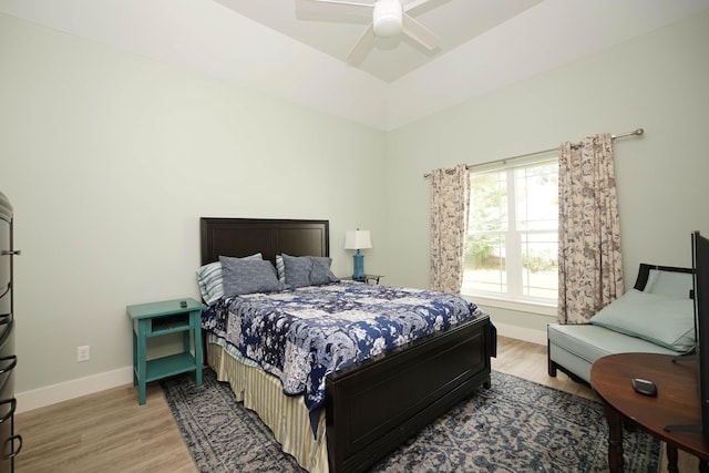 bedroom with a ceiling fan, baseboards, and light wood finished floors